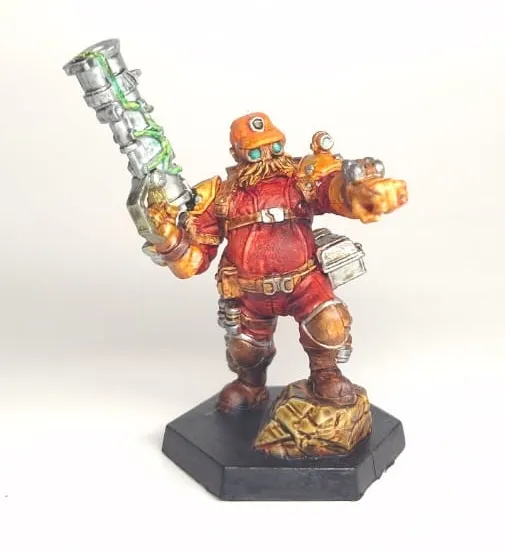 Painted dwarf miniature in red armour holding a heavy weapon